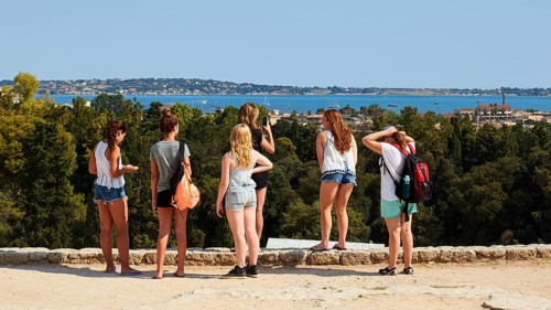 Group of young people looking at a landscape with sea and trees on a sunny day, Neapolis
