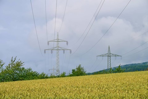 Crop field under cloudy sky with electricity pylons, summer, Germerode, Geo nature park Park