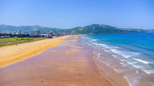 Aerial view of zarautz beach and town on a sunny summer day, showing the golden sand, blue water,