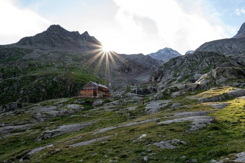 Mountain hut Elberfelderhütte in front of a rocky mountain landscape, sun star in the morning, in