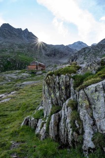 Mountain hut Elberfelderhütte in front of a rocky mountain landscape, sun star in the morning, in