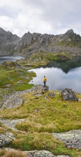 Mountaineer on a rock in front of mountain lakes Wangenitzsee and Kreuzsee, cloudy mountain peaks