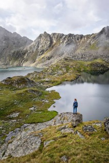 Mountaineer on a rock in front of mountain lakes Wangenitzsee and Kreuzsee, cloudy mountain peaks
