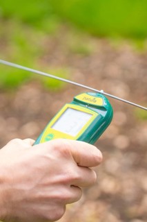 Hand holding an electronic device near a wire fence, Waldweide Gechingen, compensation project for