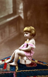 Child sitting on chamber pot, 1920s, A small child sits on a potty, smiles and wears old-fashioned