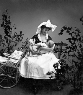 Motherly love, mother breastfeeding baby, 1930s, mother breastfeeding baby next to a cart, black