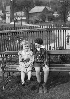 Two girls sitting on a park bench, 1930s, Two laughing children sitting next to each other on a