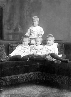 Small children sitting on sofa, 1930s, Four children in classic clothes sitting together on a couch