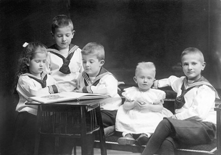Group photo of small children, 1930s, Five children in sailor suits reading a book together and