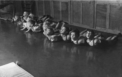 Group of children doing gymnastics, 1930s, children doing floor exercises in a row on the floor,