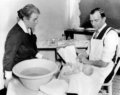 Man practising handling a baby with a doll, 1940s, A man and a woman caringly looking after a baby,