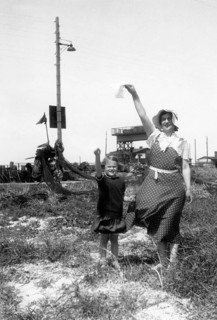 Woman and child saying goodbye, 1930s, Woman and child raising their hands in the air in greeting,