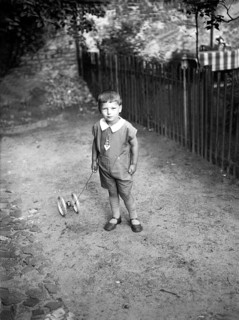 Child with toys ca. 1930s, Little boy with a toy trolley on a pavement, looking seriously into the