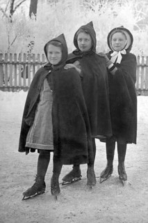 Three girls skating, 1930s, Three girls in hooded coats standing close to each other on an ice