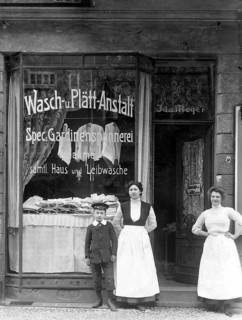 Washing and plating shop ca. 1915, woman and a boy in front of an antique shop with a window
