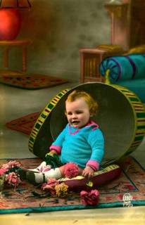 Child sitting in hatbox, 1905, A child sits in a half-opened, large Easter egg prop with flowers,