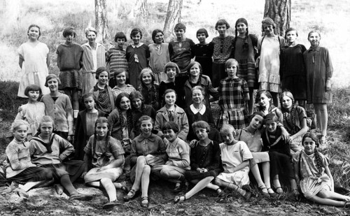 Girls class outing, 1930s, Large group of girls in school uniforms sitting outside in a wooded