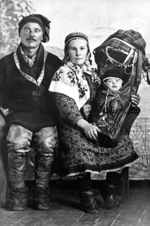 Sami in traditional dress with baby, 1930s, A traditionally dressed couple with a baby swaddled in