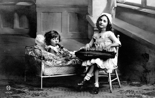 Two children making music, 1920s, Two girls, one in bed and one on a chair, playing in an old