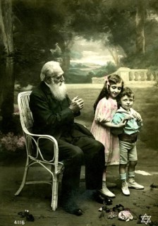 Grandpa with 2 children, 1910, An elderly man sits in the garden with two children standing happily