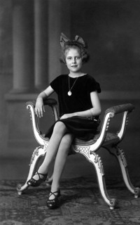 Distinguished girl, 1920, A girl sits solemnly on an ornately decorated chair, wearing a pearl