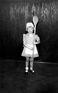 Girl with a large wooden spoon, 1930, A little girl in a costume proudly holds an oversized wooden