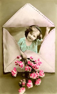 Child in an envelope, 1910, Girl looking through a heart-shaped envelope and holding flowers,