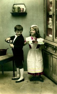 Boy and girl as servants, 1920s, A boy and a girl playing in an old kitchen with apple juice and