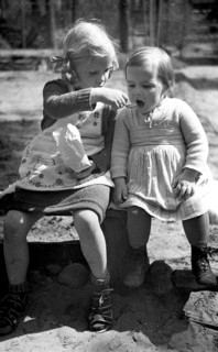 Girl feeding girl, 1930, Two little girls sharing a snack in a warm and friendly scene, Historical