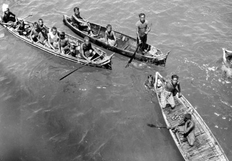 Children in catamarans, Asia, 1930s, People in boats paddling together on a river or lake,