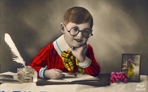Little boy with colourful clothes sitting at desk and writing love letter, 1920s, Child with