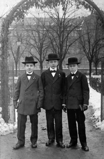 Young men, 1920s, Three boys in elegant clothes and hats stand under an arch on a snowy day,