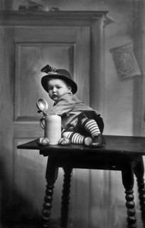 Baby traditional traditional costume beer mug, 1930s, child in traditional dress sitting on a table