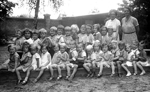 Kindergarten, 1920s, group of children and two woman outdoors, cheerful atmosphere, black and