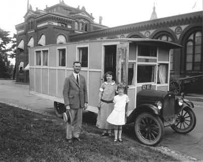 Caravan, 1930s, family in front of a historic car, possibly a mobile home, in front of an old