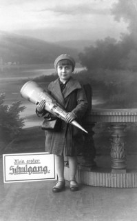School enrolment, 1920s, A boy with a school bag poses in front of a picturesque landscape,
