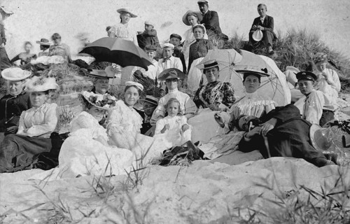 Large group of holidaymakers sitting in dunes, 1910s, Group of woman and men sitting on a sunny