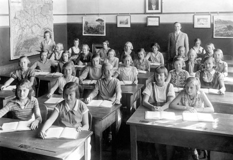 School class girls, 1930s, pupils and teacher in a classroom with maps on the walls, historical