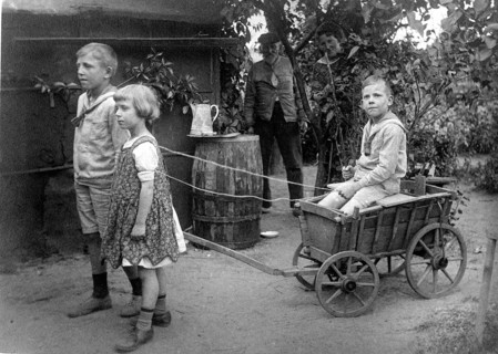 Children playing with carts, 1920s, children pulling a wooden cart in the garden, playful and