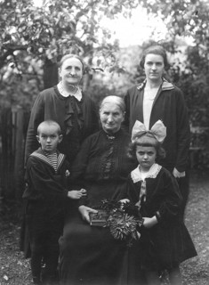 Family photo, 1920s, Three generations pose for a portrait in the garden with flower decoration,