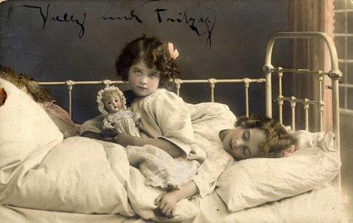 Two girls in bed, 1920s, Two children in bed, one awake with doll, the other asleep, atmospheric,