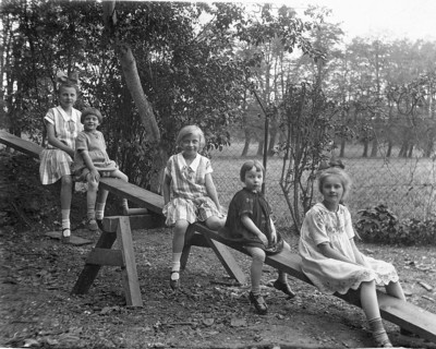 Five children on a seesaw, 1920s, Five children sitting on a swing outdoors, black and white
