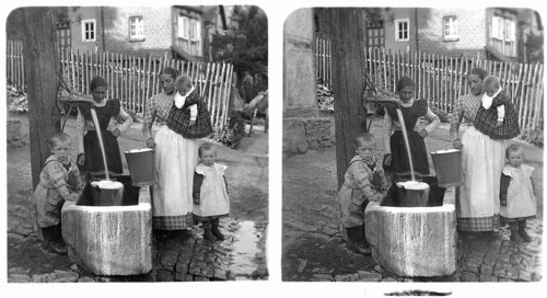 Women fetching water, 1920s, Women and children at water pump in courtyard, showing everyday scene,