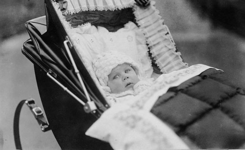 Baby in pram, 1920s, Baby lying in an old-fashioned pram, looking into the camera, black and white,
