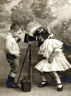 Children's camera self-timer 1906, Two children playing with an old camera, one looking at the