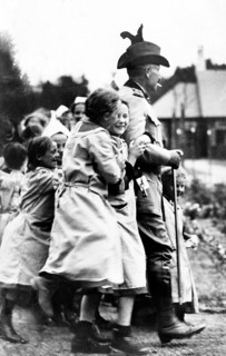 Kaiser Wilhelm with children, children laughing and playing around a uniformed man outdoors,