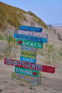 Wooden signs with colourful lettering stand in the dune sand on the beach, beach section 27,