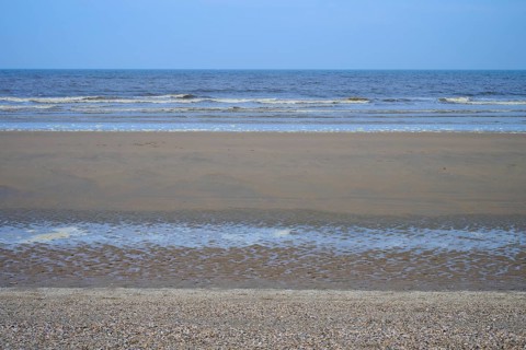 View of a wide sandy beach with gentle waves under a clear sky, beach section 27, Noordwijk, North