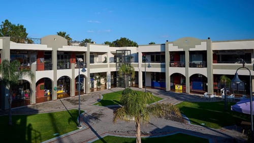 Modern shopping centre with arcades, green areas and balconies under sunny skies, Marina Centre,