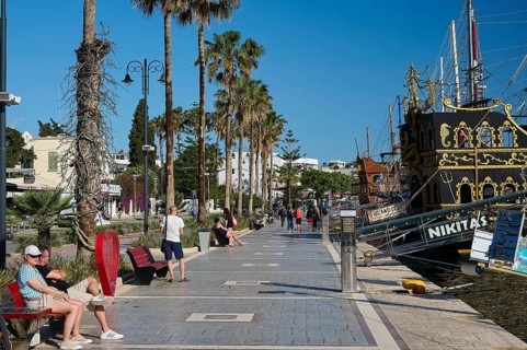 Promenade with palm trees and a sailing ship in the background, relaxed atmosphere, harbour